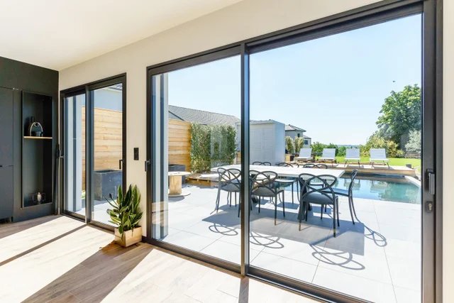 Baie vitrée coulissante aluminium ouverte sur terrasse