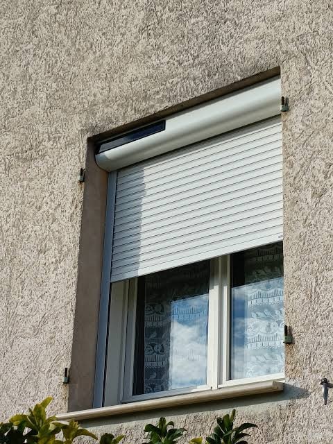 Volet roulant blanc semi-fermé sur fenêtre — pose en rénovation